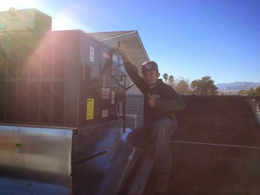 HVAC technician performing AC Tune-Up on a rooftop unit in Gilroy